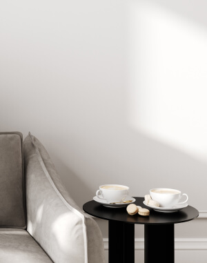 a black table with two white cups and saucers on it next to a gray couch