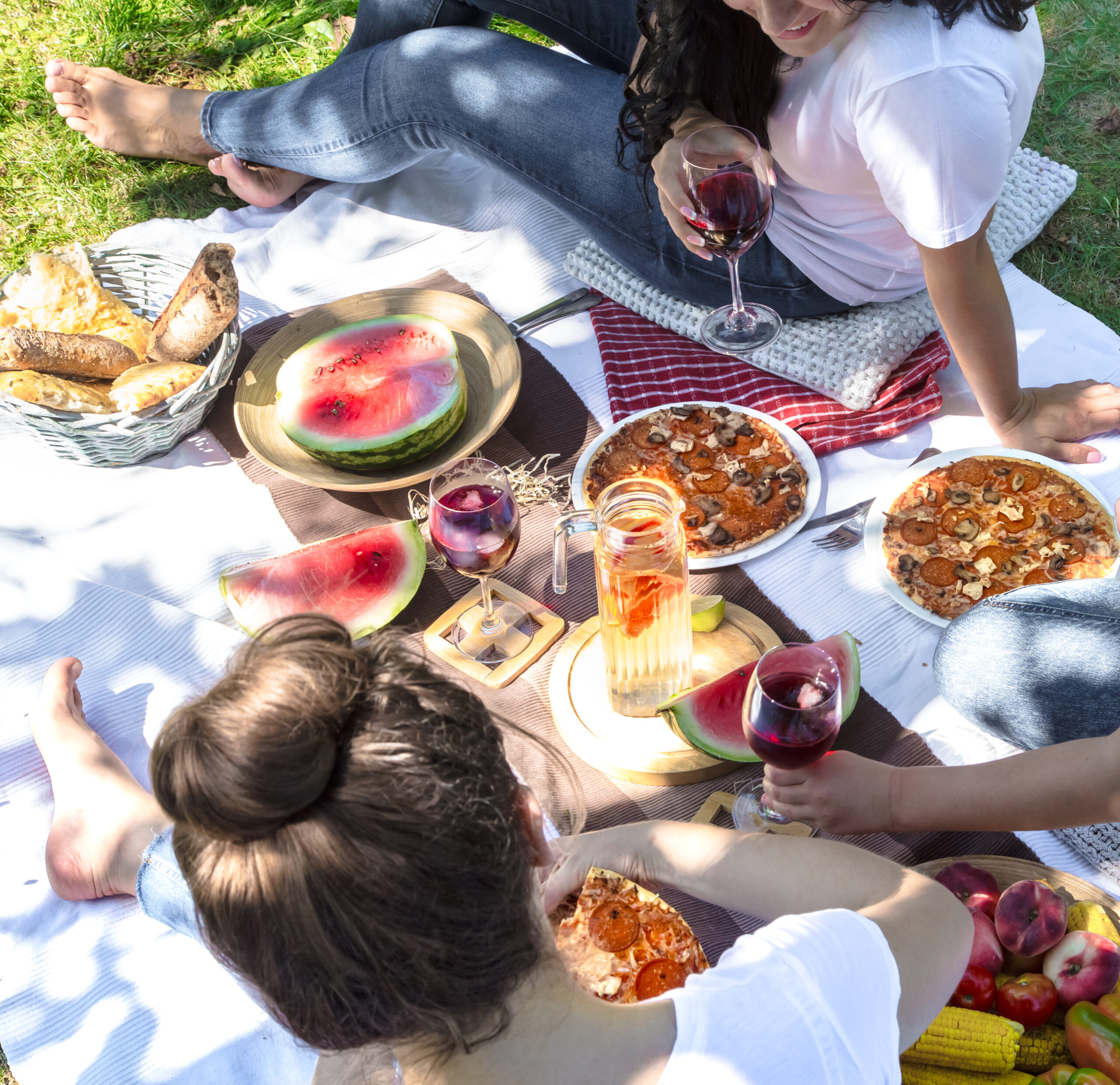 summer picnic with friends with watermelon, pizza, wine, tea, and other small snacks