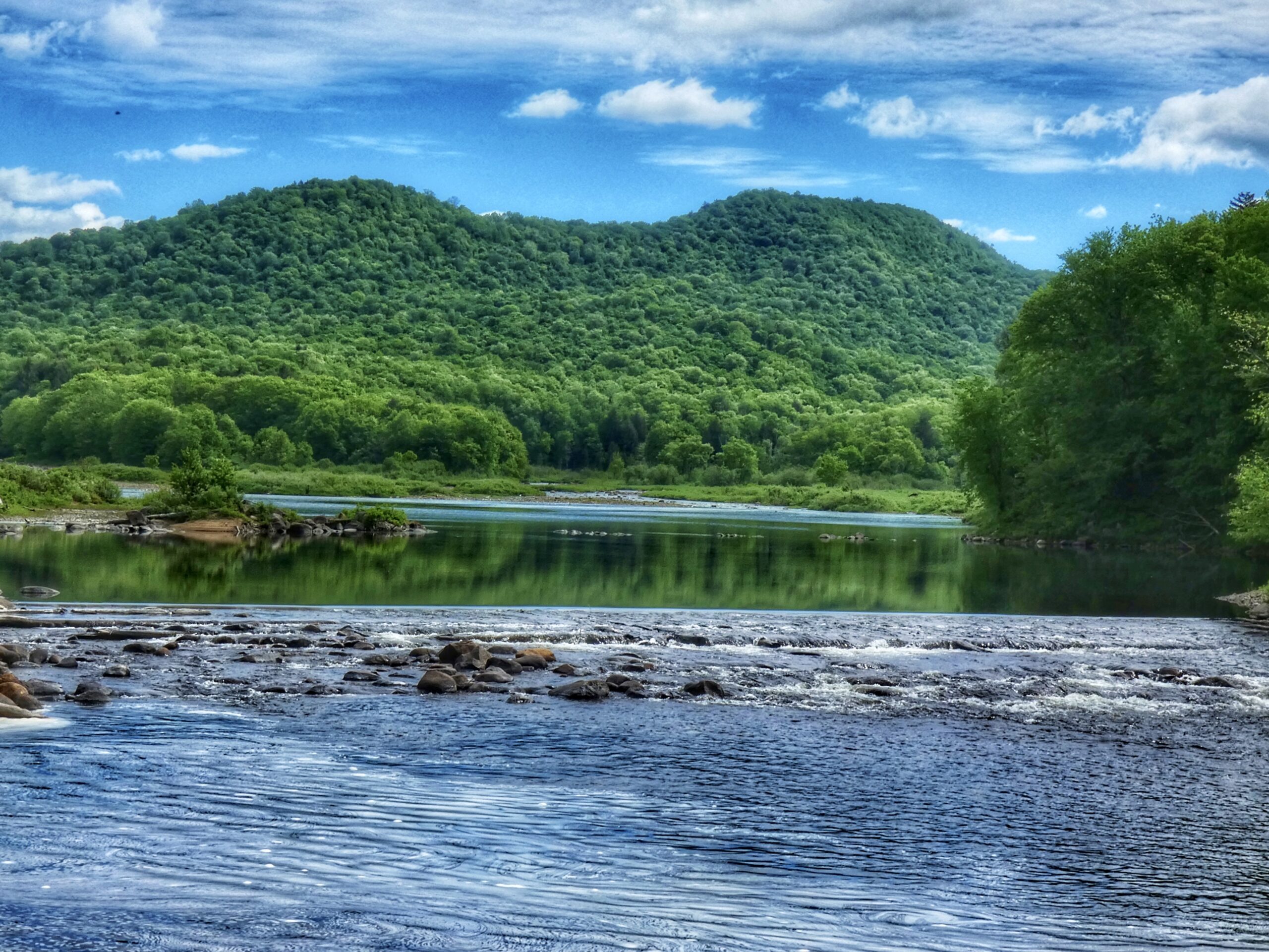 River with rocks and rolling green hills behind